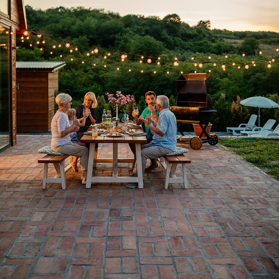 Multigenerational family sitting at an outdoor dining table at dusk.