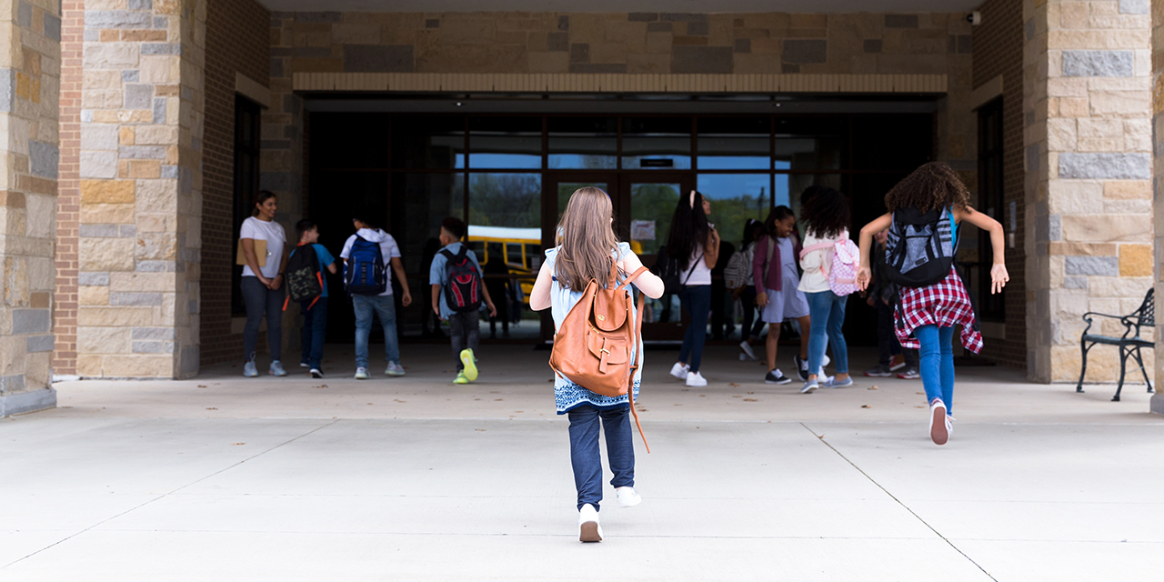 School ages girl walking into school building
