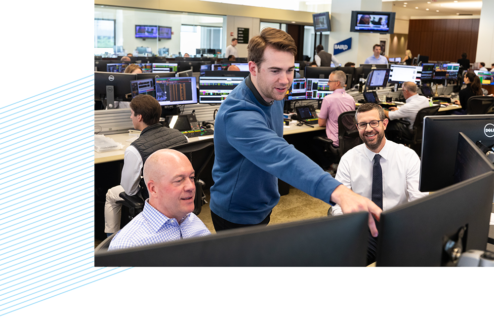 Three Nexus associates looking at computer monitors on the trading floor